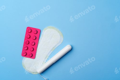 Preview: Contraceptive pills, hygienic pads and tampons on blue background