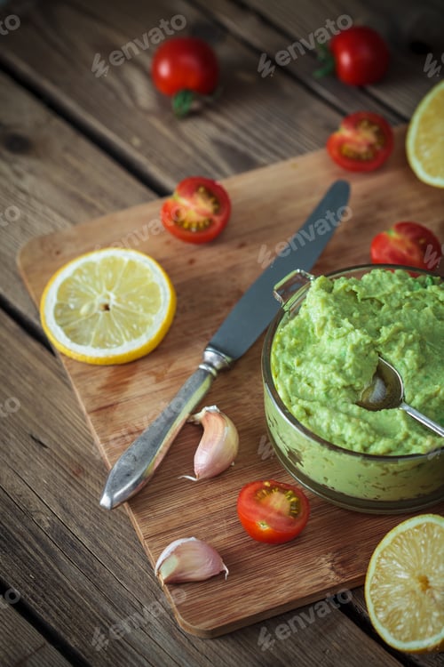 Preview: Guacamole on wooden table surrounded by its ingredients