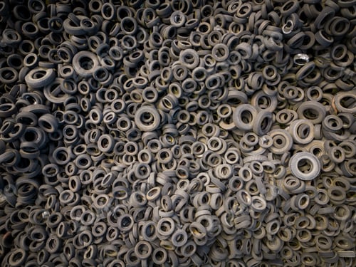 Preview: Aerial view of the stark contrast between a massive landfill of used car tires and the surrounding