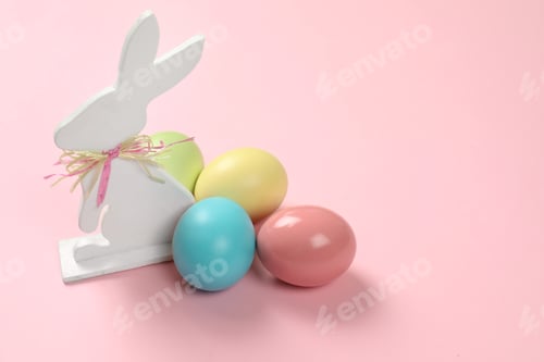 Preview: Cute wooden Easter bunny and dyed eggs on color background, space for text