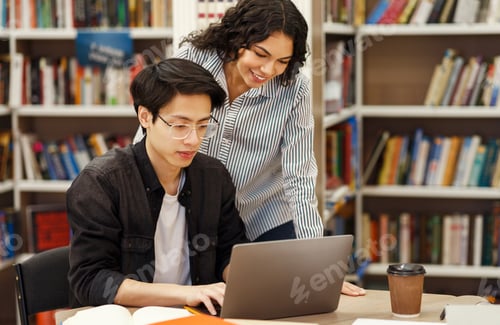 Preview: Latin counselor standing and looking at student's work