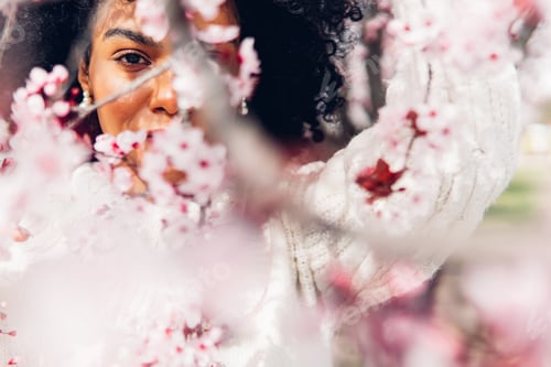 Preview: Woman surrounded by pink flowers in spring season.