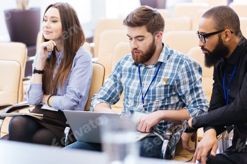 Preview: Young business people using laptop sitting on meeting