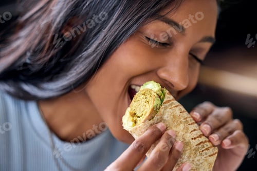 Preview: Ive never been so hungry in my life. Shot of a young woman enjoying a wrap during lunch.