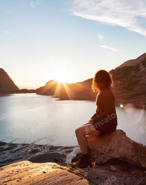 Preview: Adventurous Caucasian Adult Woman Hiking on top of a Canadian Rocky Mountain