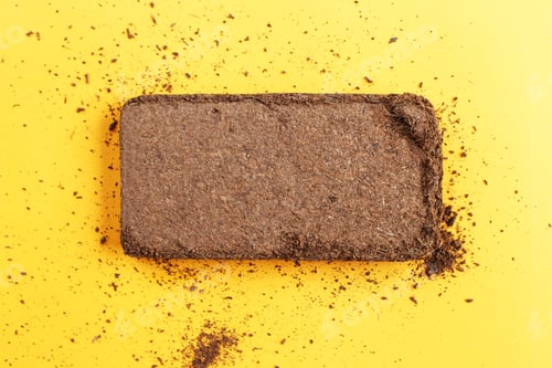 Preview: soil texture close up. mock up. coconut briquette on a orange background