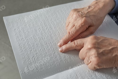 Preview: Blind senior person reading book written in Braille, closeup