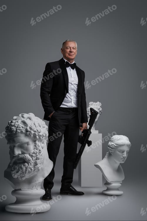 Preview: Stylish older man in expensive suit holding gun surrounded by ancient sculptures