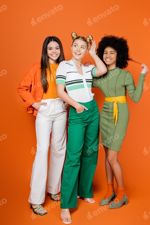 Preview: Full length of cheerful and confident multiethnic teen girlfriends in trendy outfits posing while