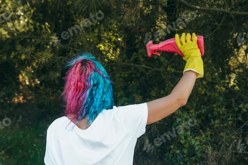 Preview: A female with yellow gloves holding a plastic cleaning spray bottle - plastic pollution concept