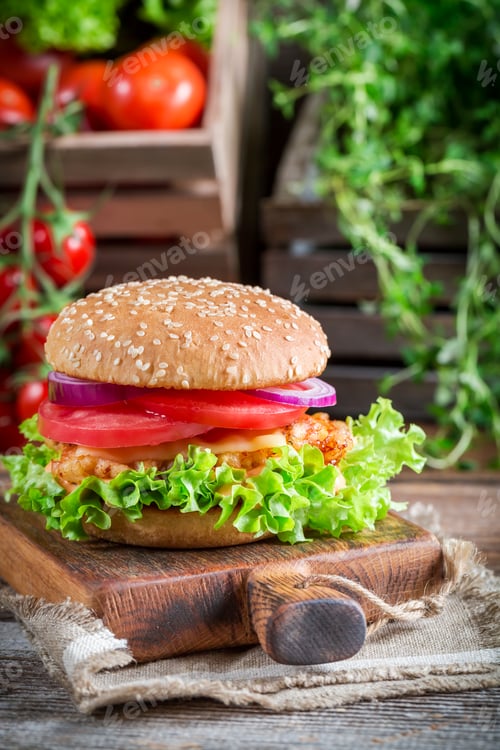 Preview: Tasty burger with chicken on old wooden table