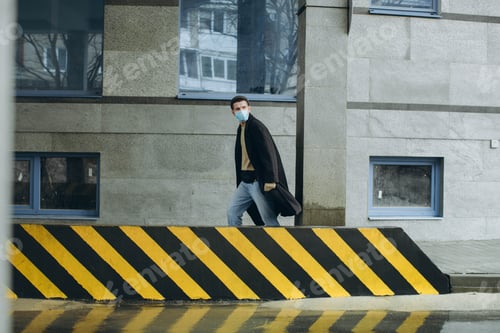 Preview: young man with a mask outdoors on urban background. Protection against virus and grip