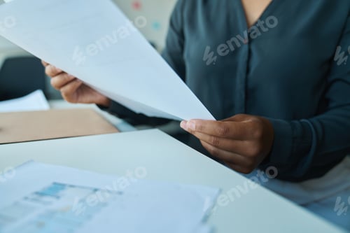 Preview: Woman sits table and holds sheet of paper in her hands