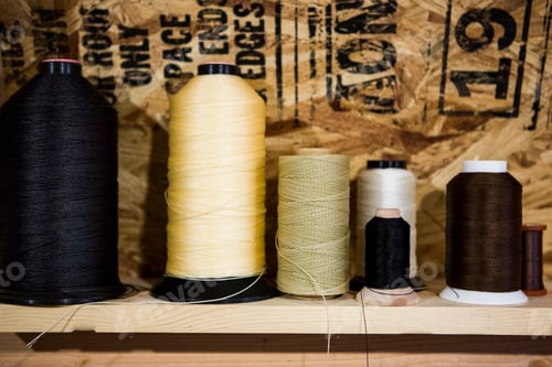 Preview: Row of thread bobbins on workshop shelf