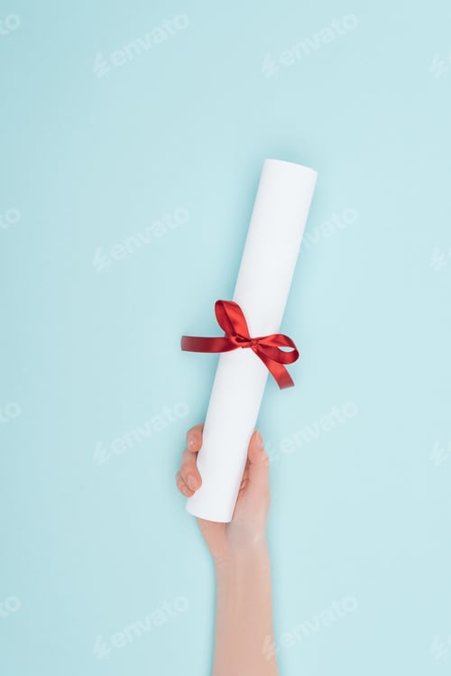 Preview: Cropped view of woman holding diploma with ribbon on blue surface