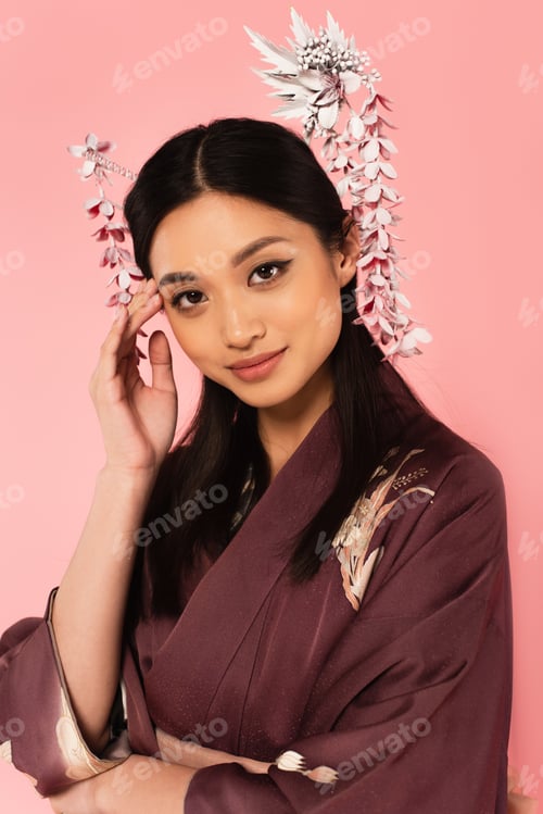 Preview: Asian woman with hairsticks in hairdo posing isolated on pink
