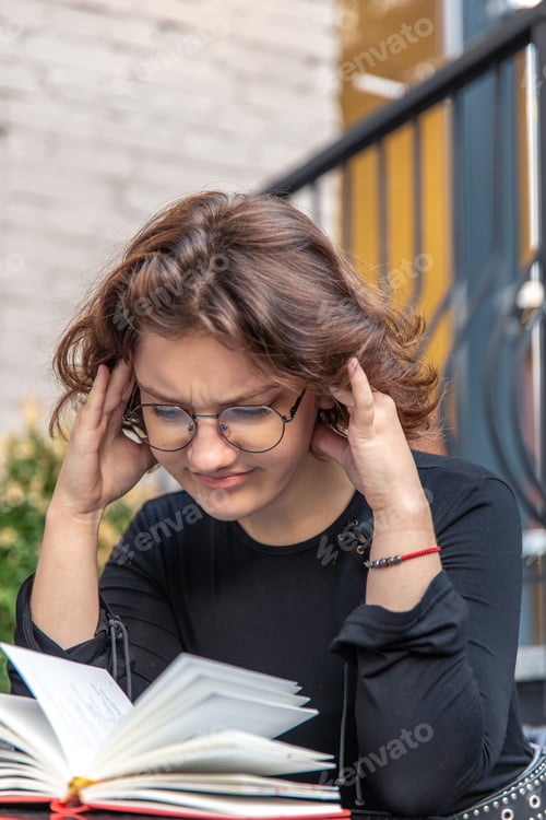 Preview: A stressed young woman is reading a book. Emotions concept.