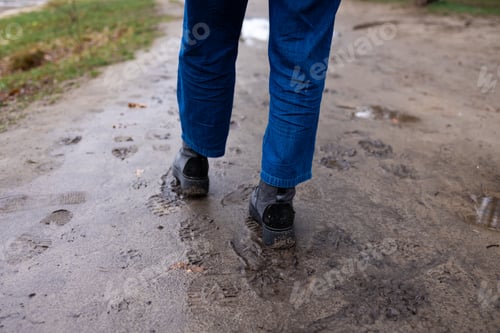 Preview: Back view of a boots covered in mud taken while walking after rain.