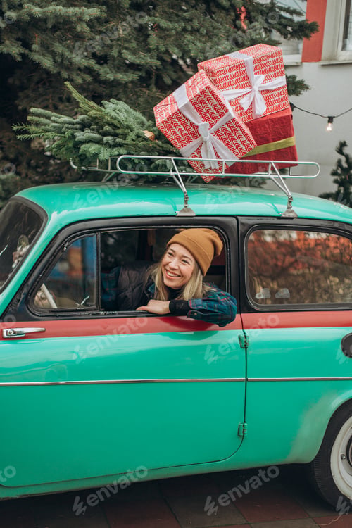 Preview: Young blonde woman sitting in retro car with Christmas decorations