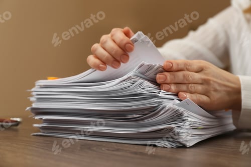 Preview: Woman stacking documents at wooden table indoors, closeup