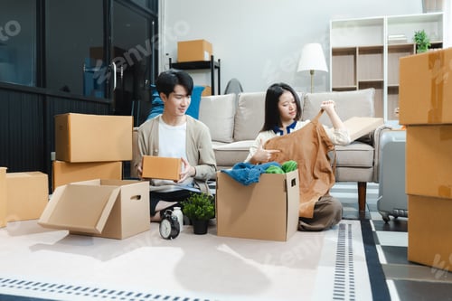 Preview: Young couple relaxing sitting on the floor around cardboard boxes at home