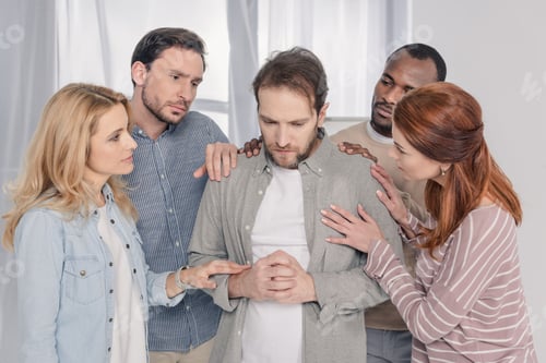 Preview: middle aged multiethnic people supporting sad man during group therapy