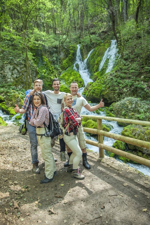 Preview: Group of friends posing in front of a beautiful waterfall on a sunny day