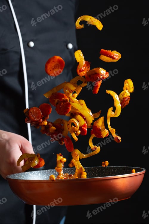 Preview: Chef cooking vegetables on a pan. Black background. Freeze movements