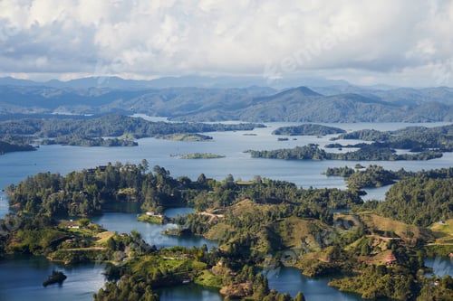 Vorschau: Luftaufnahme der Stadt Guatape in Kolumbien mit Bergen und bewölktem Himmel im Hintergrund