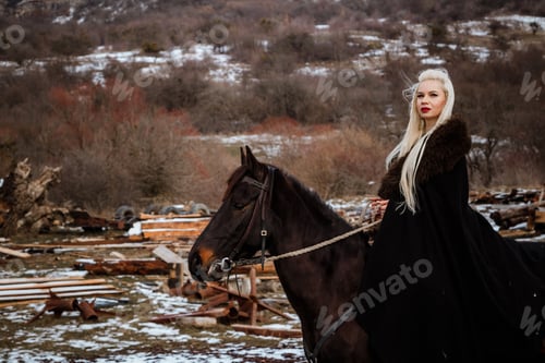 Preview: Woman viking with a black horse against the background of mountains