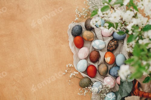 Preview: Easter eggs on rustic background with basket, spring flowers and green branches