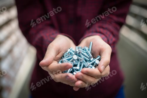 Preview: persons hand hold silver bolts close up concept b