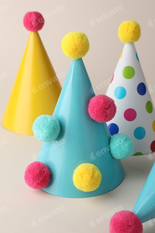 Preview: Colorful party hats with pompoms on beige background