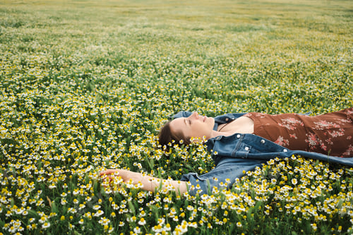 Preview: Happy woman lying in a green chamomile field