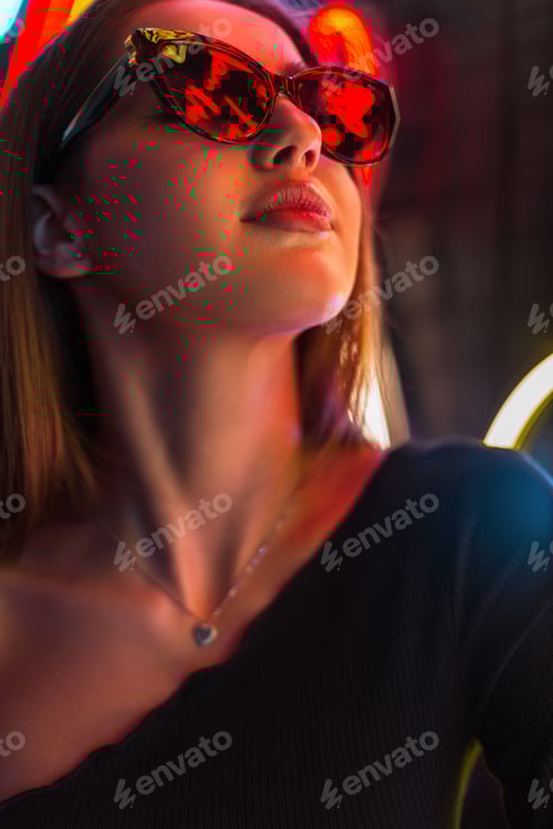 Preview: Happy beautiful fashion girl with stylish glasses near multicolored neon lights