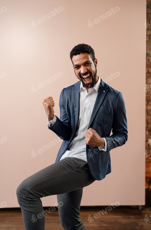Preview: Happy young succeeful businessman yes gesturing and showing fist, studio shot.