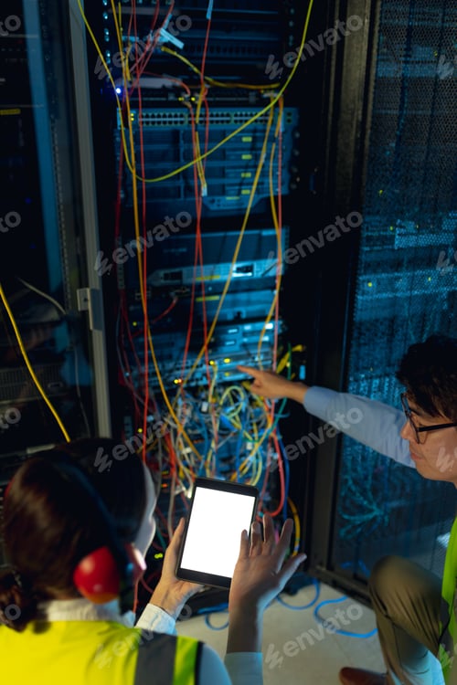 Preview: Diverse male and female engineer using digital tablet while inspecting in computer server room