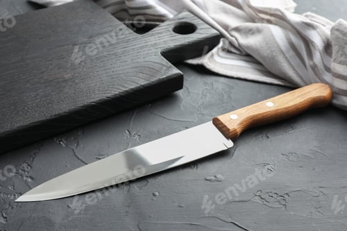 Preview: One sharp knife and board on dark textured table, closeup