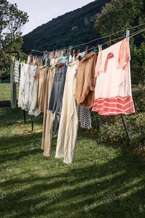 Preview: Freshly washed clothes hang on clotheslined outside in a grassy countryside