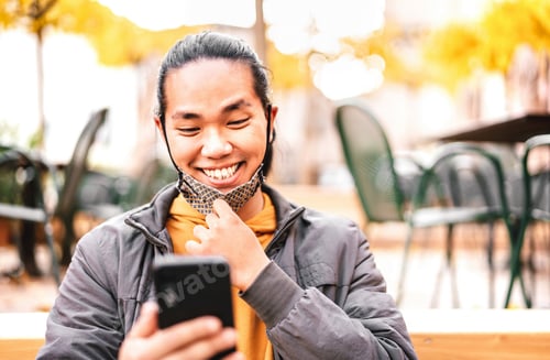 Preview: Happy asian guy smiling with open face mask after lockdown reopening