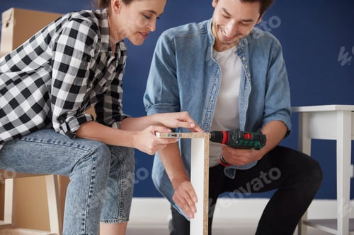 Preview: Couple using electric drill to install furnitures