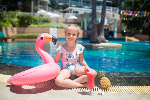 Preview: Happy little Caucasian girl with blonde hair wearing swimsuit and sunbathing near swimming pool