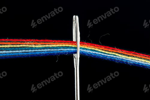 Preview: multi-colored threads for sewing in the form of a rainbow pass through an antique needle