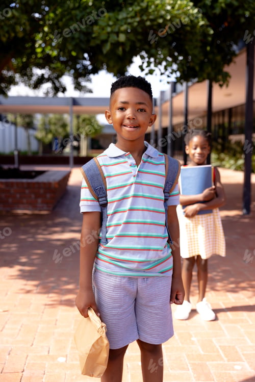 Preview: Portrait of happy african american schoolboy standing in school yard