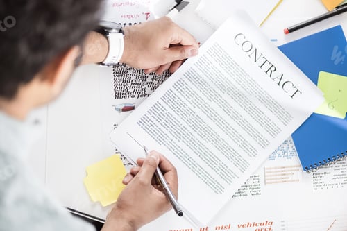 Preview: Overhead view of businessman holding contract above table with papers