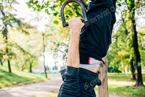Preview: Man training outdoor in a park using rings