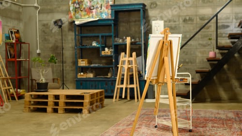 Preview: Bright and open art studio with industrial style walls with wooden easels and painting supplies