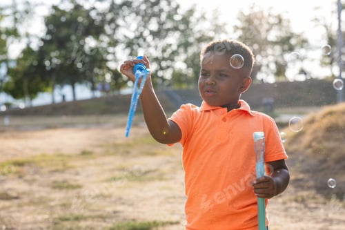 Preview: Young boy blowing soap bubbles outdoors in park