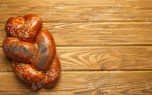 Preview: Freshly baked Challah bread covered with poppy and sesame seeds, top view on rustic wooden