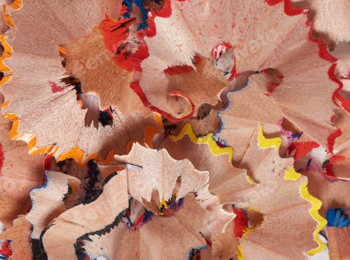 Preview: Colorful pencil shavings in red, yellow, blue, and wood tone. The shavings are curled and layered